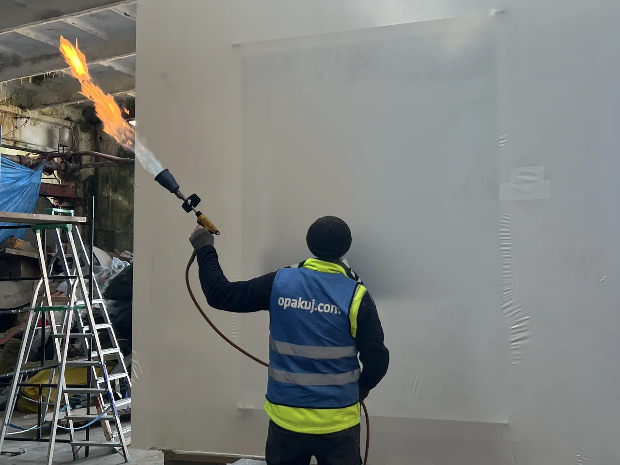 Obkurczanie folii termokurczliwej palnikiem gazowym na hali